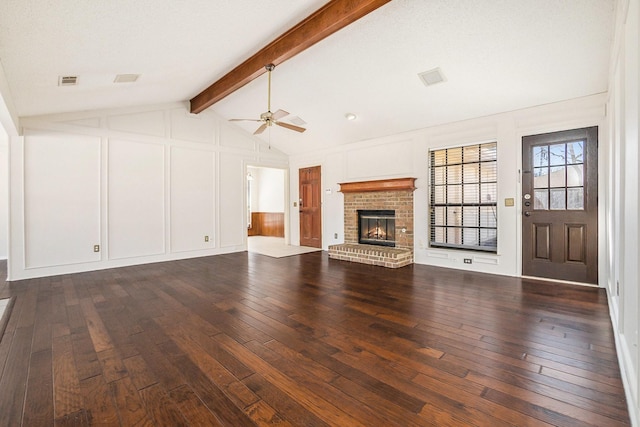 unfurnished living room with lofted ceiling with beams, dark wood-style flooring, a fireplace, and a decorative wall