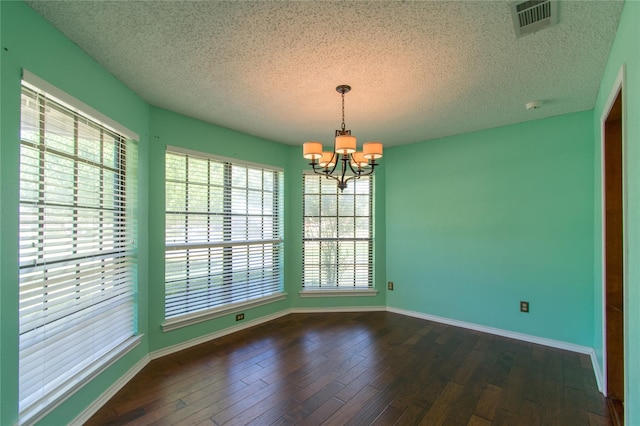 unfurnished room with a textured ceiling, a notable chandelier, and dark hardwood / wood-style flooring