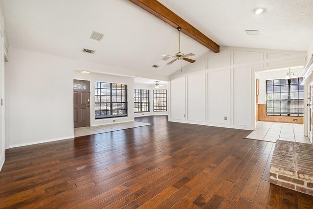 unfurnished living room featuring ceiling fan, vaulted ceiling with beams, a textured ceiling, dark hardwood / wood-style flooring, and a brick fireplace