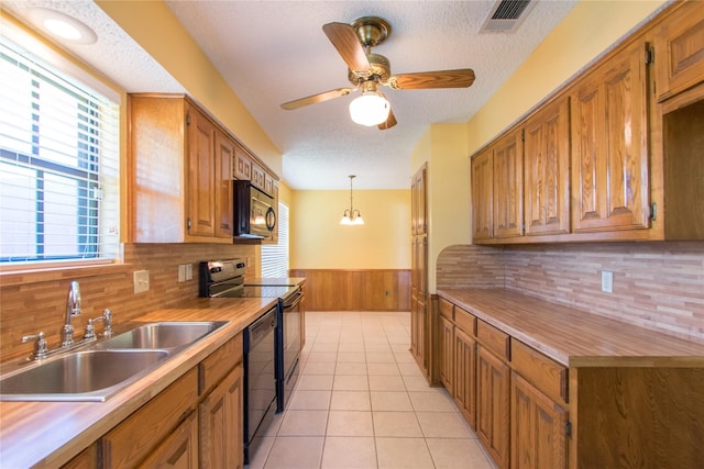 kitchen featuring sink, hanging light fixtures, light tile patterned floors, black appliances, and a textured ceiling