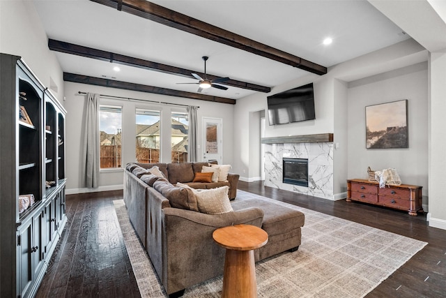 living room featuring ceiling fan, a high end fireplace, dark hardwood / wood-style floors, and beam ceiling