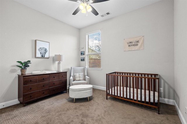 carpeted bedroom featuring visible vents, baseboards, a nursery area, and ceiling fan