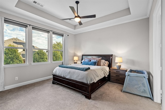 bedroom featuring visible vents, ornamental molding, a tray ceiling, baseboards, and light colored carpet