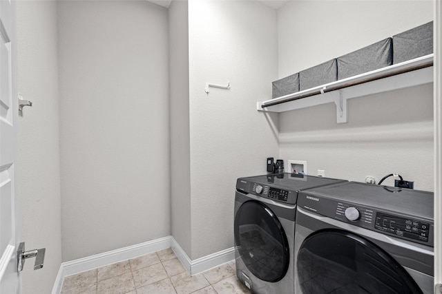 laundry room featuring light tile patterned flooring, laundry area, washing machine and dryer, and baseboards