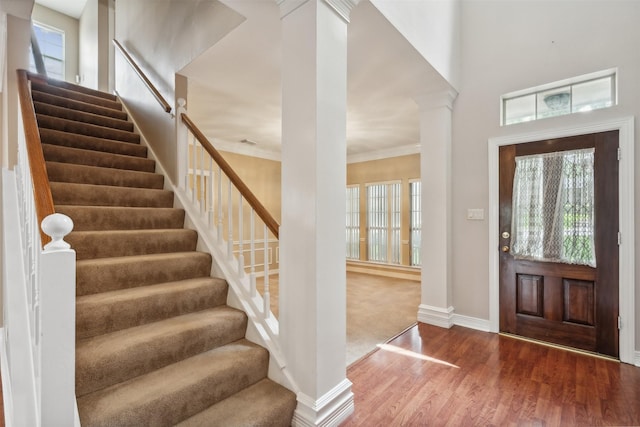 entryway featuring ornate columns, wood-type flooring, and ornamental molding