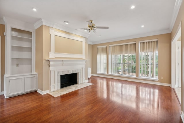 unfurnished living room featuring a fireplace, ornamental molding, ceiling fan, and light wood-type flooring