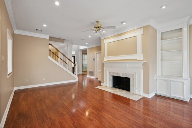 unfurnished living room with built in features, a fireplace, decorative columns, hardwood / wood-style flooring, and crown molding