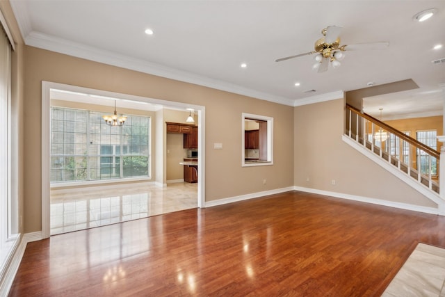 unfurnished living room with crown molding, wood-type flooring, and ceiling fan with notable chandelier