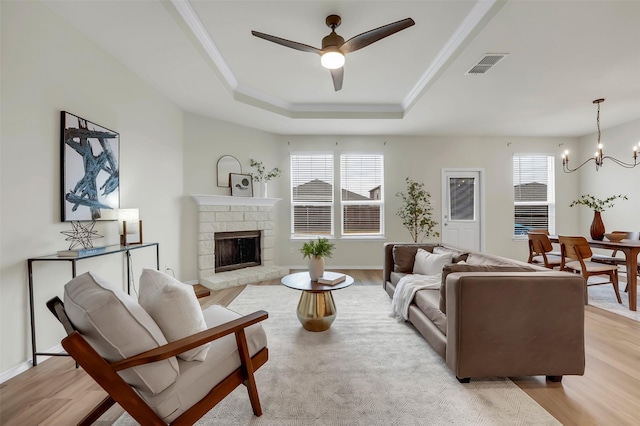 living room featuring crown molding, ceiling fan with notable chandelier, light wood-type flooring, and a tray ceiling