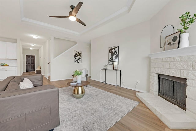 living room with crown molding, hardwood / wood-style floors, a fireplace, and a tray ceiling