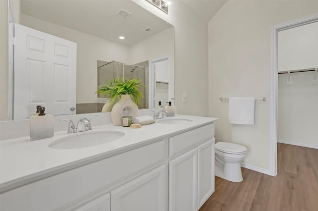 bathroom with a shower with door, vanity, hardwood / wood-style floors, and toilet