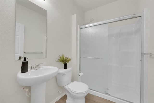 bathroom with wood-type flooring, toilet, and a shower with door