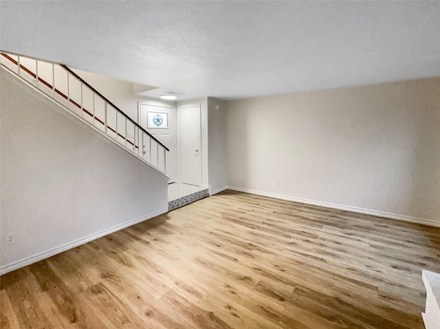 unfurnished living room featuring a textured ceiling and light hardwood / wood-style floors