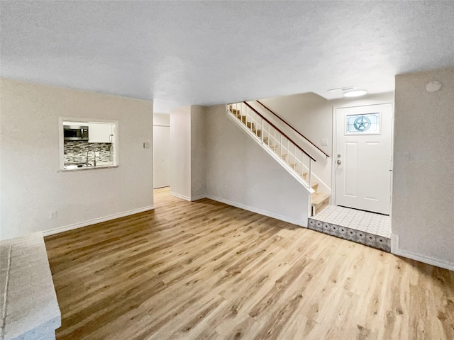 unfurnished living room featuring hardwood / wood-style floors, sink, and a textured ceiling