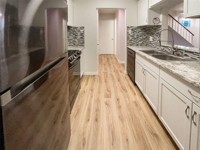 kitchen with sink, white cabinets, light stone counters, black appliances, and light wood-type flooring