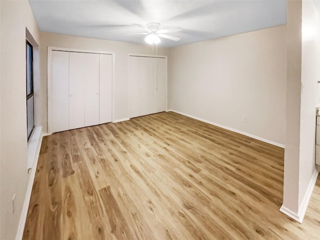 unfurnished bedroom with multiple closets, ceiling fan, and light hardwood / wood-style floors