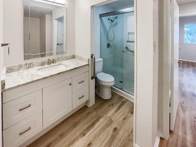 bathroom featuring vanity, wood-type flooring, toilet, and walk in shower