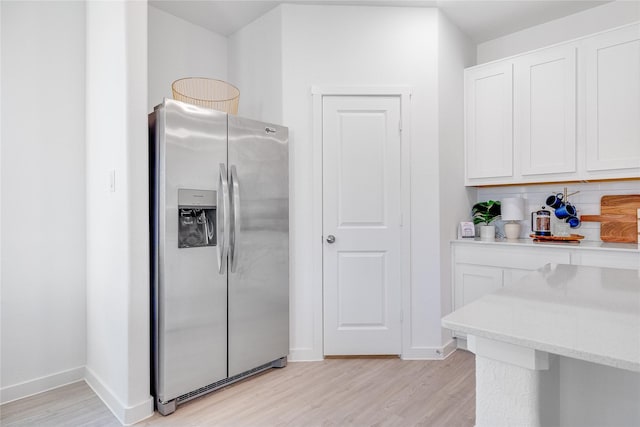 kitchen with white cabinetry, stainless steel fridge, light hardwood / wood-style flooring, and backsplash