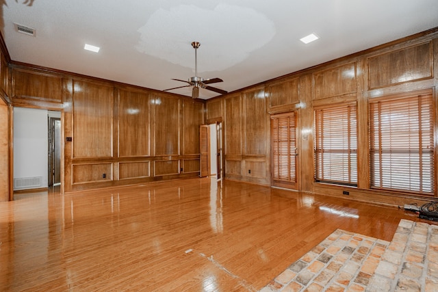 spare room with hardwood / wood-style flooring, ceiling fan, and wooden walls