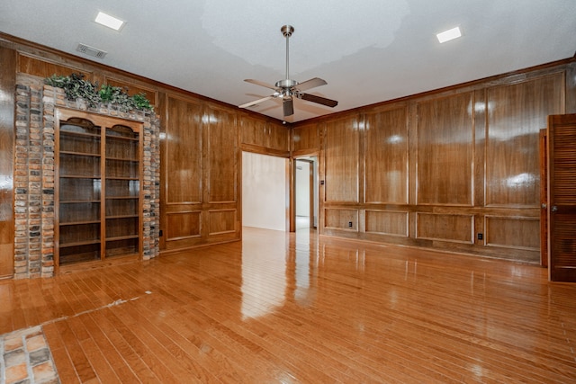 unfurnished living room with ceiling fan, hardwood / wood-style floors, and wooden walls