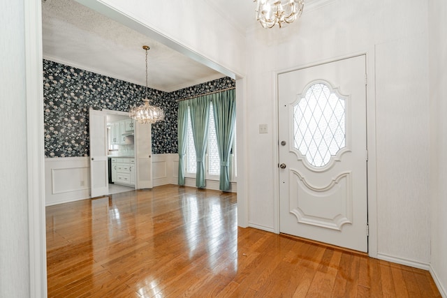 foyer with crown molding, a chandelier, and hardwood / wood-style flooring