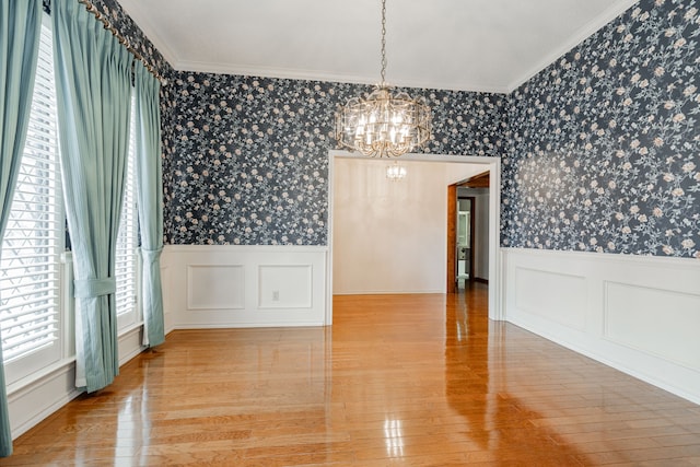 unfurnished dining area featuring crown molding, a chandelier, and hardwood / wood-style flooring