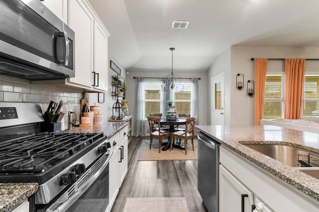 kitchen featuring light stone countertops, backsplash, stainless steel appliances, and white cabinets