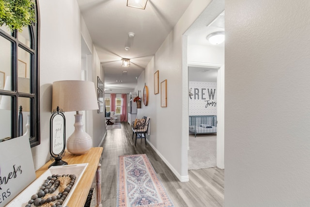 corridor featuring wood finished floors and baseboards