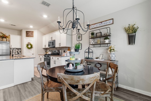 dining room with sink, an inviting chandelier, and dark hardwood / wood-style floors