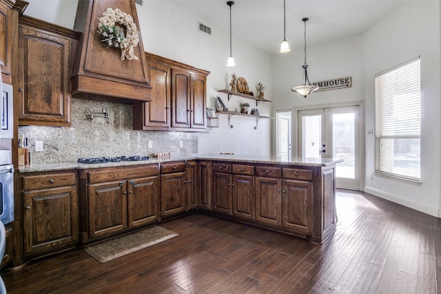 kitchen featuring premium range hood, dark hardwood / wood-style floors, decorative light fixtures, stainless steel gas stovetop, and french doors