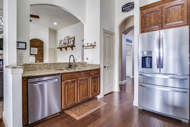 kitchen featuring light stone counters, stainless steel appliances, dark hardwood / wood-style floors, and sink