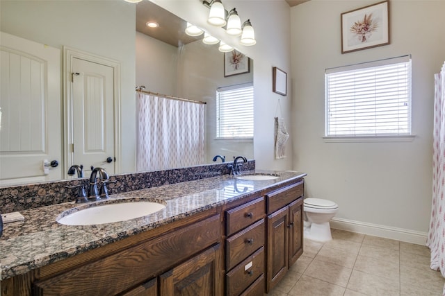 bathroom with vanity, toilet, tile patterned flooring, and a wealth of natural light