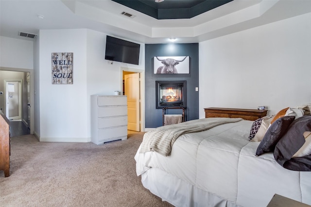 bedroom with a raised ceiling, a towering ceiling, and light carpet