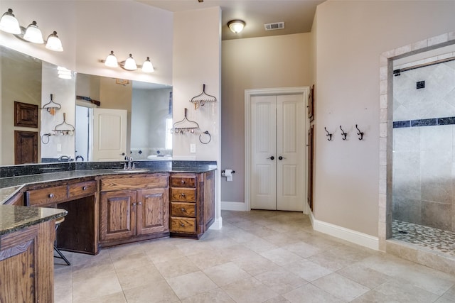 bathroom featuring tile patterned flooring, vanity, and a tile shower