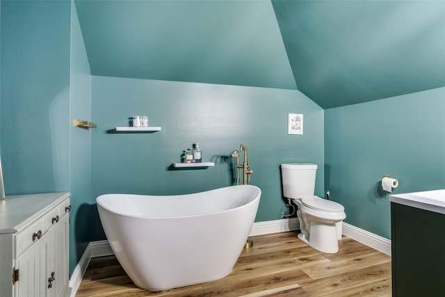 bathroom with vanity, lofted ceiling, hardwood / wood-style floors, and a tub to relax in