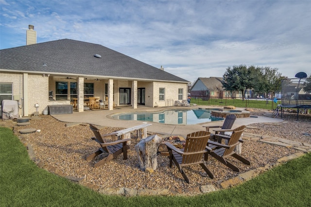 view of swimming pool featuring an in ground hot tub, ceiling fan, a patio, and a trampoline