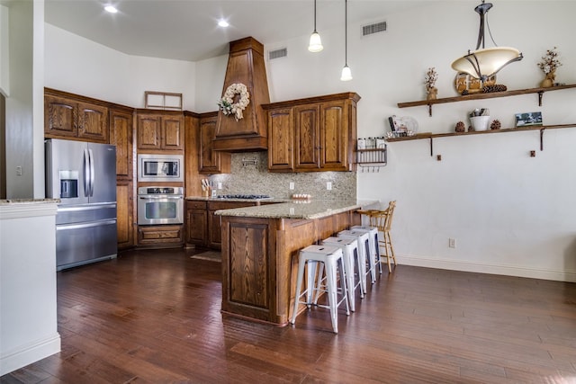 kitchen featuring light stone counters, tasteful backsplash, hanging light fixtures, a kitchen breakfast bar, and stainless steel appliances