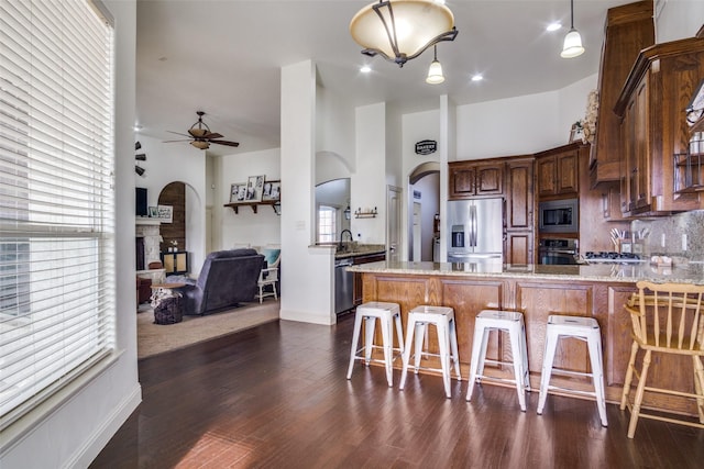 kitchen featuring a breakfast bar, light stone counters, appliances with stainless steel finishes, kitchen peninsula, and backsplash