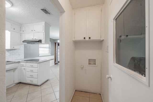 kitchen with black electric cooktop, light tile patterned floors, decorative backsplash, and white cabinets