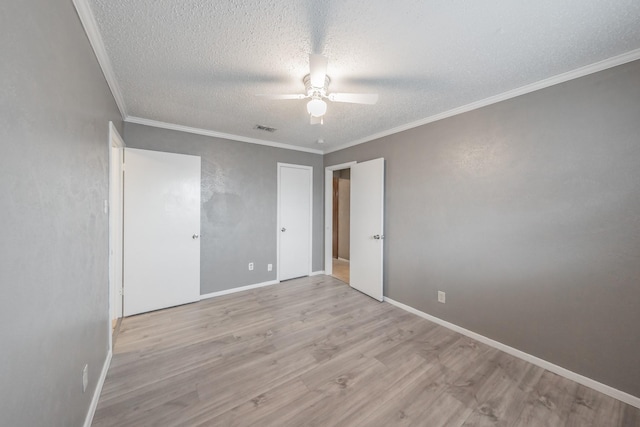 spare room featuring ceiling fan, light hardwood / wood-style flooring, ornamental molding, and a textured ceiling