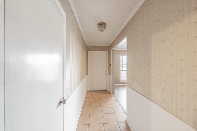 corridor featuring light tile patterned floors, crown molding, and a textured ceiling