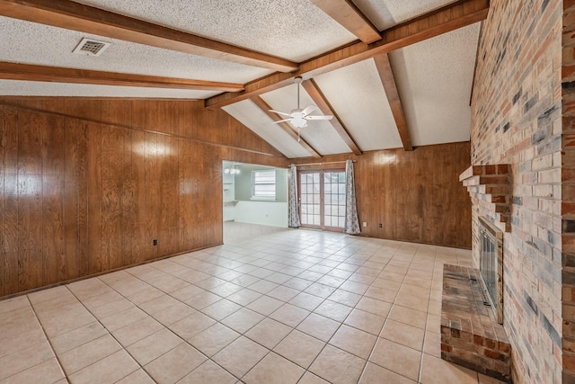 unfurnished living room featuring light tile patterned floors, ceiling fan, a fireplace, a textured ceiling, and wood walls