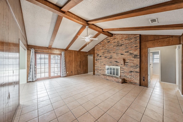 unfurnished living room featuring light tile patterned floors, a fireplace, wooden walls, and a textured ceiling