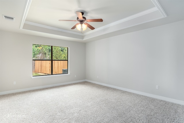 carpeted empty room featuring ceiling fan, ornamental molding, and a raised ceiling