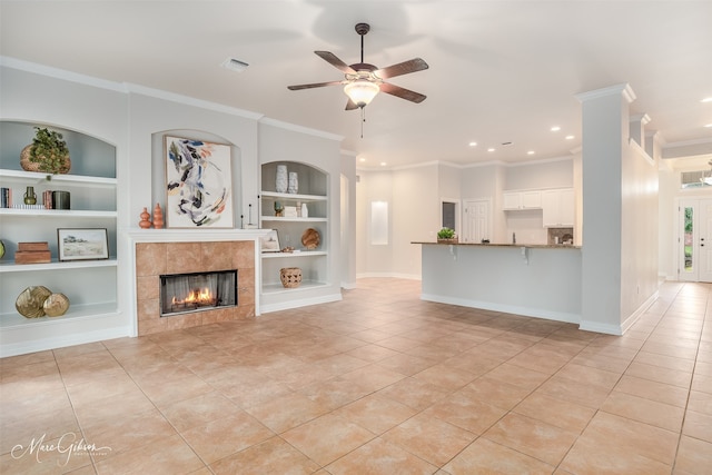 unfurnished living room featuring light tile patterned flooring, ornamental molding, a fireplace, and built in features