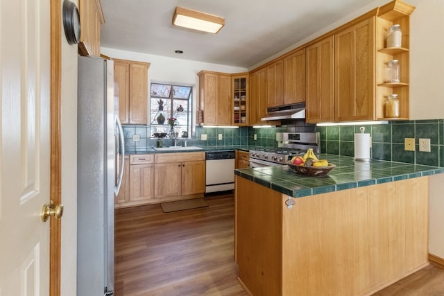 kitchen featuring stainless steel appliances, tile countertops, kitchen peninsula, and wood-type flooring