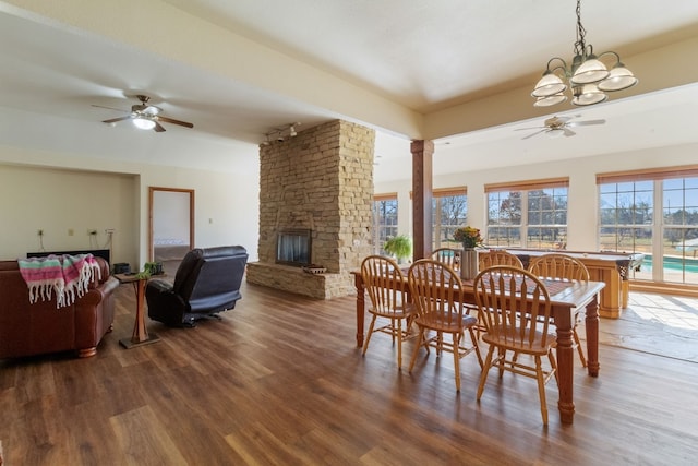 dining space with hardwood / wood-style flooring, a fireplace, decorative columns, and ceiling fan