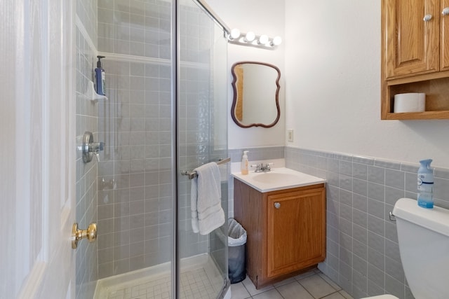 bathroom featuring tile patterned flooring, tile walls, vanity, toilet, and walk in shower