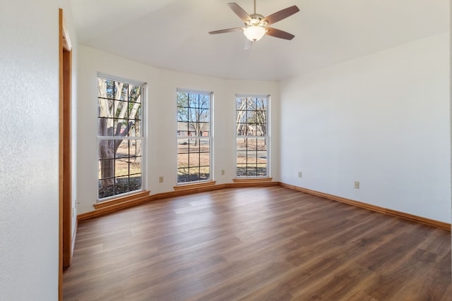 empty room with dark wood-type flooring, ceiling fan, vaulted ceiling, and a wealth of natural light