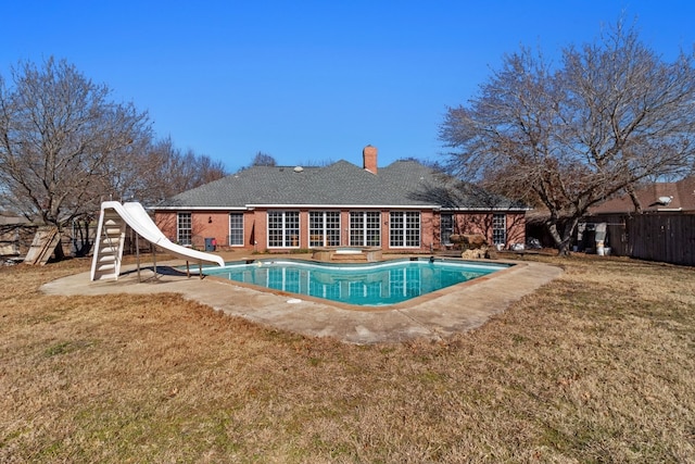 view of swimming pool featuring a water slide and a yard